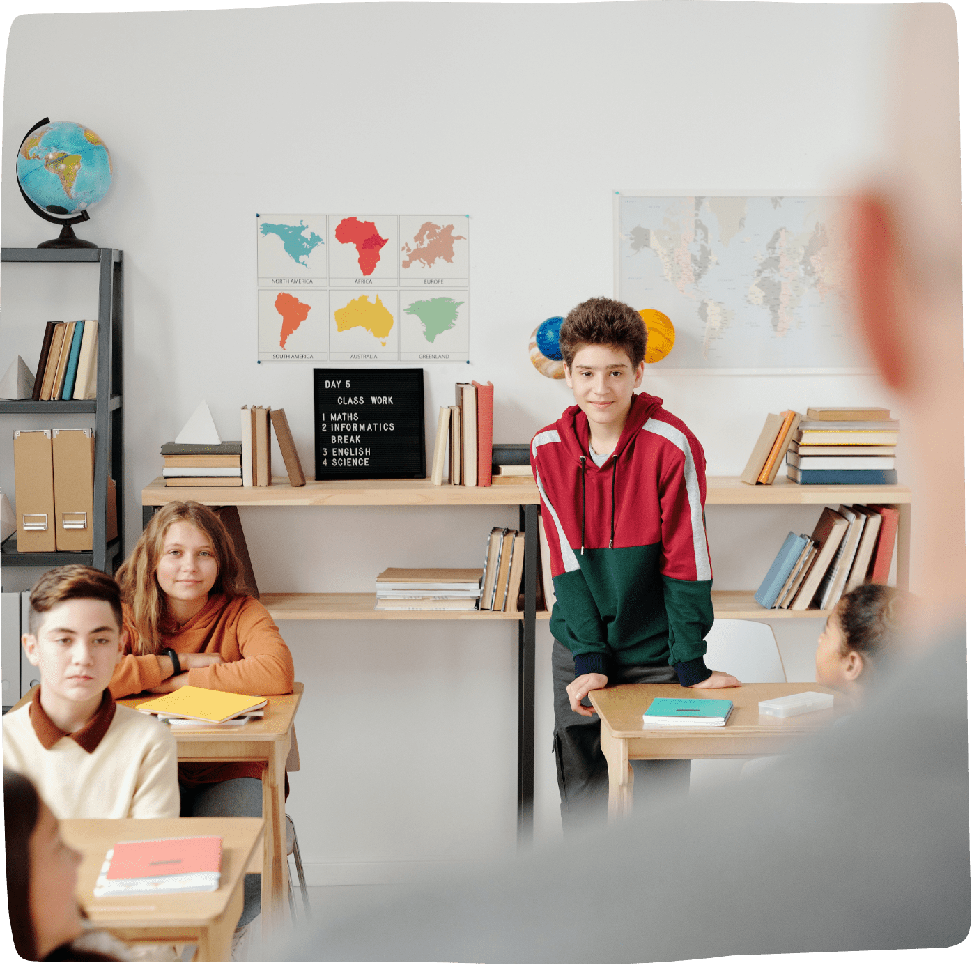 Blik over de schouder van een leraar naar een schoolklas met 6 leerlingen met lesboeken op tafel